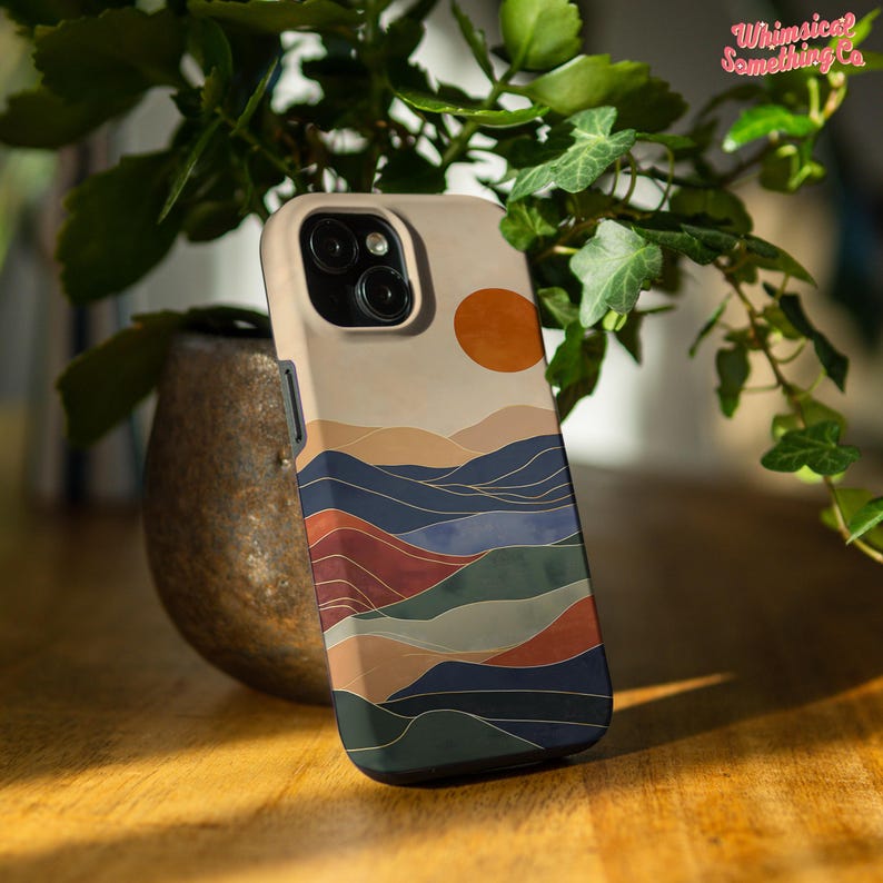 Puede incluir: Una funda para tel&eacute;fono con un dise&ntilde;o minimalista que presenta una puesta de sol sobre una cordillera en tonos azules, verdes, rojos y naranjas. La funda tiene un borde negro.