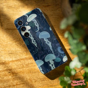 May include: A dark blue phone case with a design of white jellyfish on a dark blue background.