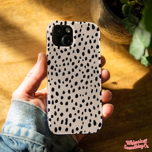 Peut inclure: Une coque de téléphone pour iPhone à imprimé dalmatien noir et blanc. La coque a un fond crème avec des taches noires.