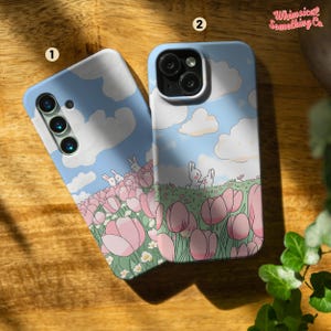 May include: Two phone cases with a whimsical design featuring a blue sky with white clouds, pink tulips, and two white rabbits. The text "Whimsical Something Co." is visible in the top right corner of the image.