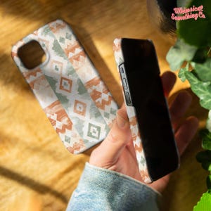 May include: Two phone cases with a geometric pattern in shades of brown, green, and white. The pattern is reminiscent of Native American art.