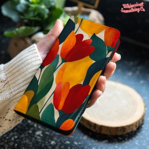 May include: A phone case with a colourful tulip pattern in red, orange, and yellow. The design is set against a cream backdrop, with green borders. The text "Whimsical Something Co." is visible in the upper right corner.