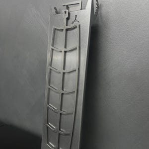 May include: A silver metal rack with a grid pattern and a hook at the top. The rack is designed to hold items like knives or other kitchen tools.