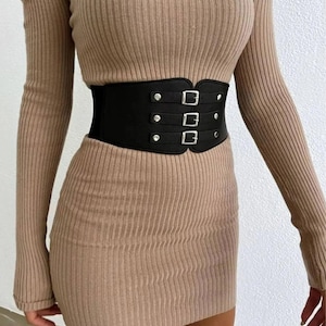 May include: A brown ribbed off-the-shoulder sweater dress with a black faux leather corset belt with silver buckles.