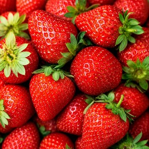May include: A collection of fresh, ripe strawberries with vibrant red skin and textured surfaces. Each strawberry features a small, green leafy calyx at the top. The fruits are clustered together, displaying their conical shapes and tiny seeds.