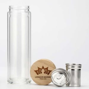 May include: A clear glass tea bottle with a bamboo lid and a stainless steel infuser. The lid has the logo "Urban Monk Tea Co." engraved on it.