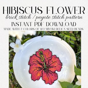 May include: A white ceramic plate featuring a beaded hibiscus flower design in shades of red, orange, and yellow. The text "HIBISCUS FLOWER" and other details are displayed above the plate. The design is made with 7 colors of 11/0 Miyuki Delica seed beads.