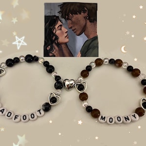 May include: Two beaded bracelets with charms and the names "PADFOOT" and "MOONY" spelled out in white letter beads. One bracelet has a star charm, the other a crescent moon. The bracelets are black, brown, and clear.