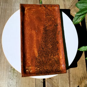 May include: A rectangular ceramic tray featuring a glossy finish with a two-tone color scheme. The left side is a smooth, solid reddish-brown, while the right side transitions into a heavily speckled, dark brown and black textured surface.