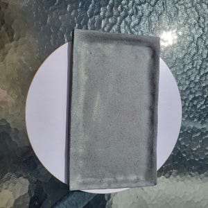 May include: A rectangular tray with a light gray speckled finish and a slightly raised edge. The surface features a matte texture with dark gray flecks distributed across the entire piece, creating a consistent and neutral appearance.