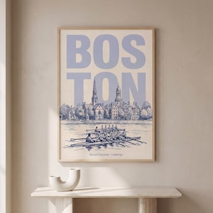 Puede incluir: Un estampado enmarcado con la palabra "BOSTON" en azul claro sobre una ilustración detallada de un horizonte urbano y un equipo de remo. El texto "Harvard University - Cambridge" está en la parte inferior.