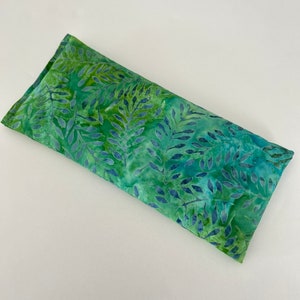 May include: A rectangular, green and blue fabric item with a fern leaf pattern. The fabric is a mix of light and dark greens with blue accents. The item appears to be a heat or cold pack.