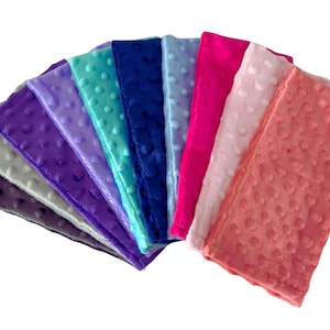 Puede incluir: Un conjunto de diez cuadrados de tela suave y afelpada en varios colores, incluyendo gris, morado, lavanda, azul verdoso, azul, rosa y coral. La tela tiene un patr&oacute;n texturizado con hoyuelos.