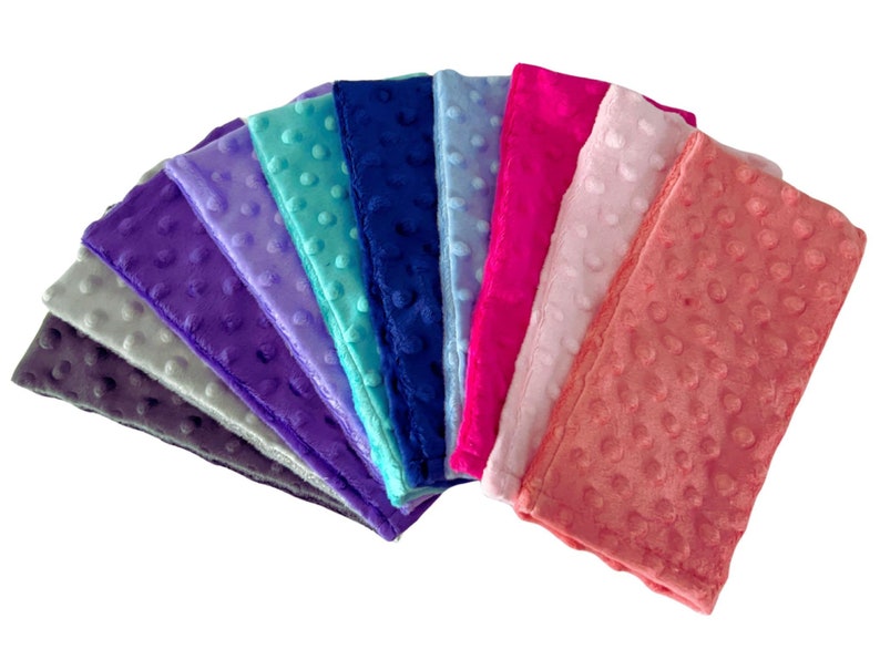 Puede incluir: Un conjunto de diez cuadrados de tela suave y afelpada en varios colores, incluyendo gris, morado, lavanda, azul verdoso, azul, rosa y coral. La tela tiene un patr&oacute;n texturizado con hoyuelos.