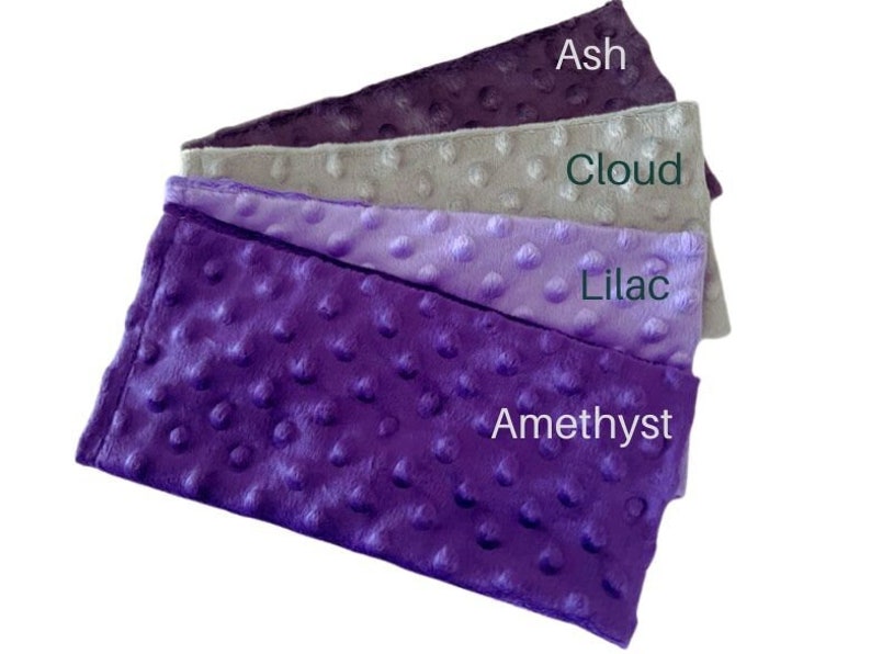 Puede incluir: Cuatro muestras de tela en tonos de morado, gris y lila. Las muestras est&aacute;n etiquetadas como "Amatista", "Lila", "Nube" y "Ceniza".