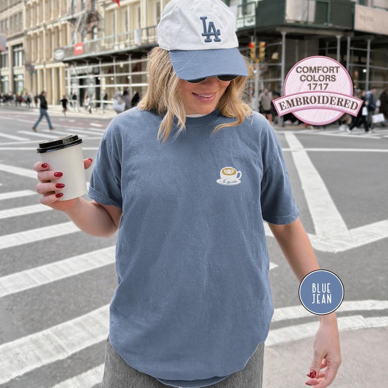 Puede incluir: Camiseta azul vaquera de manga corta con un dise&ntilde;o de taza de caf&eacute; bordada. La camiseta es de estilo Comfort Colors 1717. Se lleva una gorra de b&eacute;isbol blanca y azul.