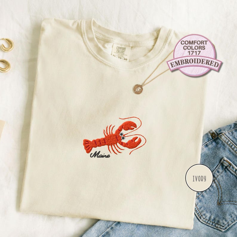 Embroidered lobster shirt featuring a red Maine lobster design on a soft coastal style t shirt, perfect for beach vacation outfits, seafood lover gifts, nautical summer wear and ocean themed casual fashion.