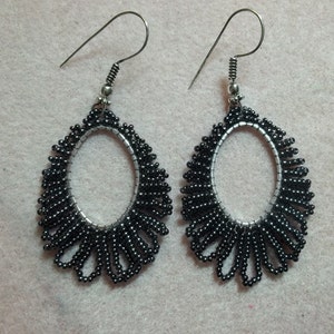 May include: A pair of black beaded earrings with silver hooks. The earrings are oval shaped and have a delicate, fringed design.