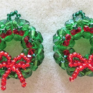 Peut inclure: Une paire de couronnes de Noël en perles vertes et rouges avec des nœuds rouges. Les couronnes sont faites de petites perles facettées et mesurent environ 5 cm de diamètre.