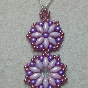 May include: A silver chain necklace with a pendant featuring two pink and purple beaded flower designs.