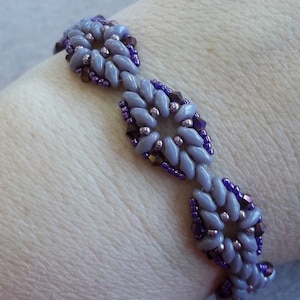 May include: A purple and silver beaded bracelet with a flower design.