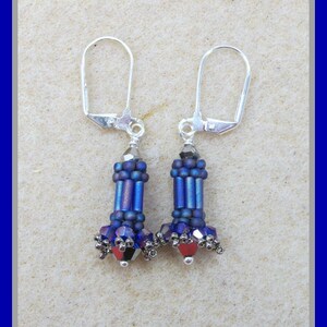 May include: A pair of silver dangle earrings with blue and red glass beads. The earrings have a silver hook closure.