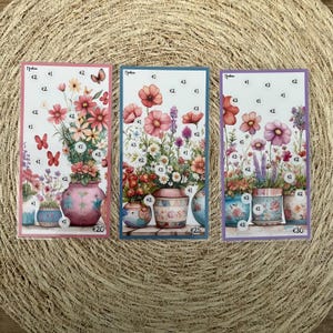 Op de afbeelding: Drie bloemenkunstprints met aquarel illustraties van bloemen in decoratieve potten. Elke print heeft een andere kleurrand: roze, blauw en paars. De prints bevatten de tekst "€1", "€2" en "€3".