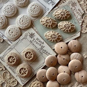 Op de afbeelding: Een verzameling vintage haakknoopjes en houten kralen. De knopen hebben verschillende vormen en ontwerpen, waaronder rond en ovaal, met ingewikkelde haakpatronen. De houten kralen zijn lichtbruin en hebben een gat in het midden. De knopen liggen op vintage kaarten.