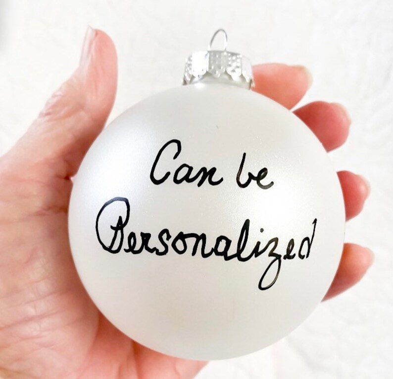 May include: White frosted glass Christmas bauble with black handwritten text that says "Can be Personalised".