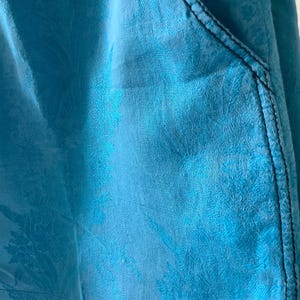 Peut inclure: Gros plan sur un tissu bleu &agrave; motif floral. Le tissu a une surface textur&eacute;e et une couture bleu fonc&eacute; le long du bord.