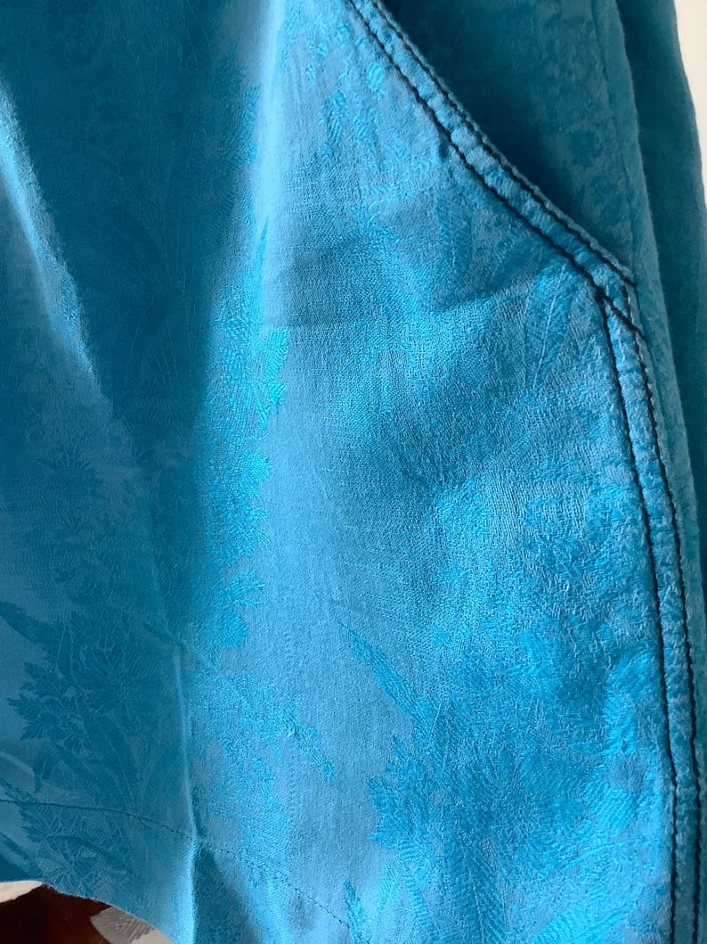 Peut inclure: Gros plan sur un tissu bleu &agrave; motif floral. Le tissu a une surface textur&eacute;e et une couture bleu fonc&eacute; le long du bord.