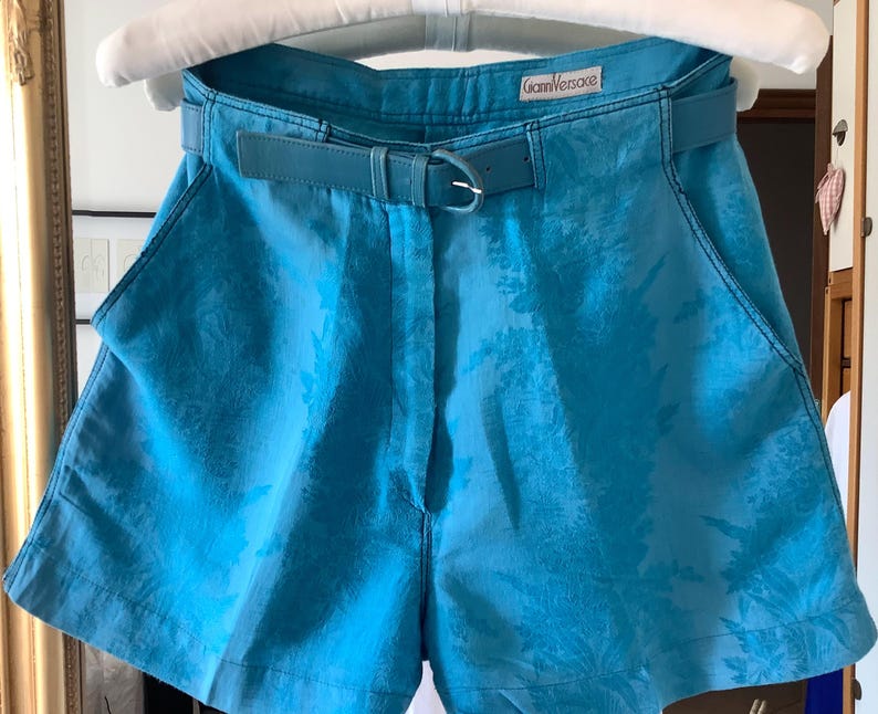 Peut inclure: Short bleu &agrave; motifs avec une ceinture noire et le texte "Gianni Versace" sur une &eacute;tiquette blanche.