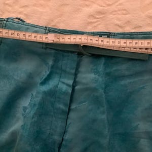 Peut inclure: Pantalon bleu sarcelle avec une ceinture et une fermeture &eacute;clair. Le pantalon a un motif floral et un m&egrave;tre ruban est plac&eacute; sur la ceinture.