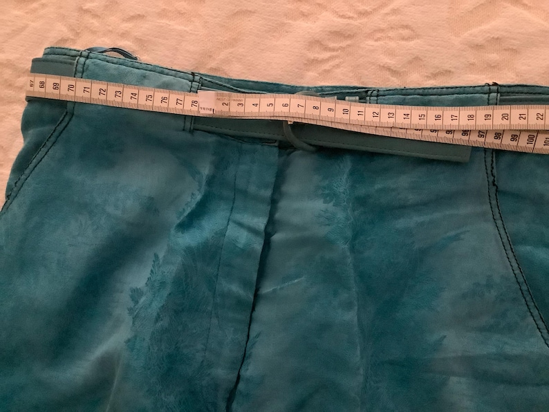 Peut inclure: Pantalon bleu sarcelle avec une ceinture et une fermeture &eacute;clair. Le pantalon a un motif floral et un m&egrave;tre ruban est plac&eacute; sur la ceinture.
