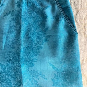 Peut inclure: Une jupe bleu turquoise &agrave; motif floral. La jupe a une ceinture et deux poches.