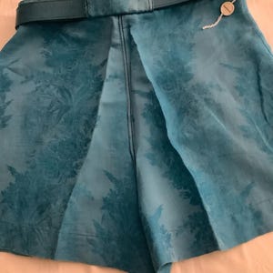 Peut inclure: Short en tissu bleu sarcelle &agrave; motif floral et ceinture en cuir marron. Les shorts ont une &eacute;tiquette attach&eacute;e &agrave; la ceinture.