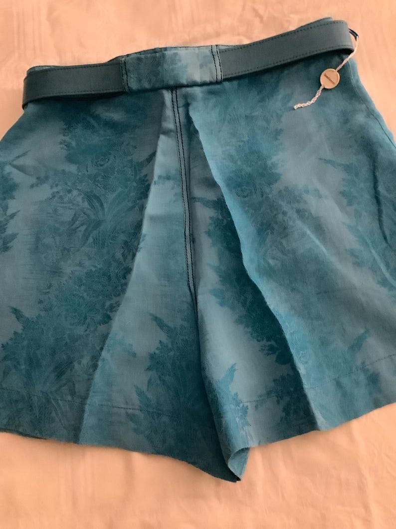 Peut inclure: Short en tissu bleu sarcelle &agrave; motif floral et ceinture en cuir marron. Les shorts ont une &eacute;tiquette attach&eacute;e &agrave; la ceinture.