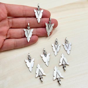 Puede incluir: Diez abalorios de punta de flecha plateados con un diseño detallado. Las puntas de flecha miden aproximadamente 2,5 cm de largo y tienen un bucle en la parte superior para sujetarlas a joyas u otras manualidades.