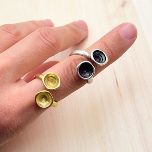 May include: Two gold and two silver rings with a unique design. The rings are open and have two round, concave, cup-like shapes on each ring.