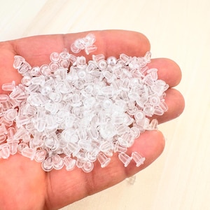 May include: A handful of clear, small earring backs. These earring backs are made of a soft, translucent plastic. The earring backs are a light, neutral color and are designed to secure earrings.