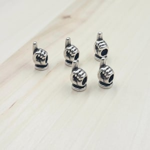 May include: Six silver charm beads in the shape of a raised index finger. The charms are designed to be used on bracelets or necklaces.