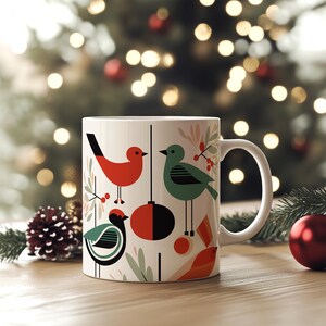 May include: White ceramic mug with a Christmas-themed design featuring red, green, and black birds, a red and black ornament, and green foliage.