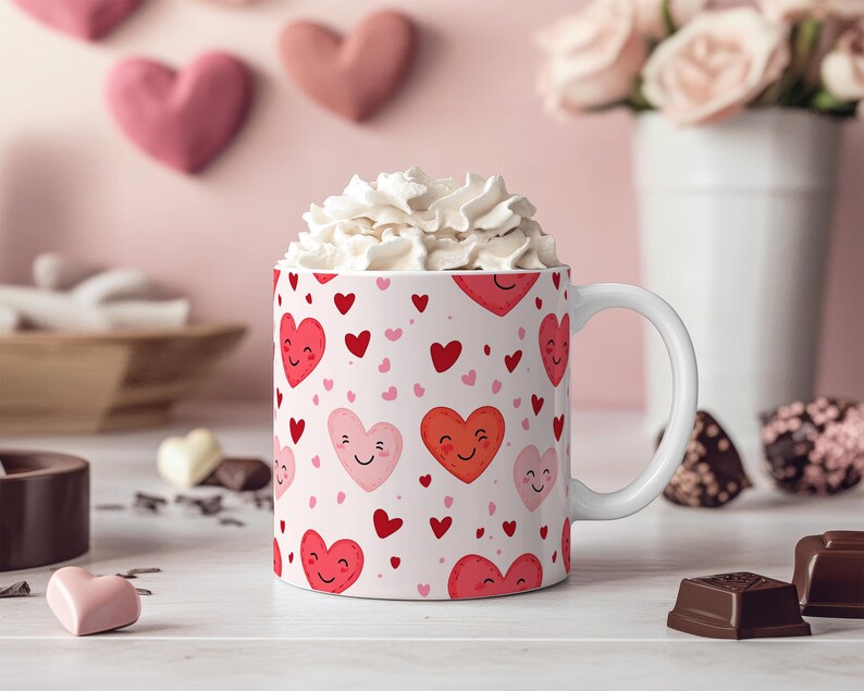 K&ouml;nnte beinhalten: Eine wei&szlig;e Keramiktasse mit einem Muster aus rosa und roten Herzen. Die Herzen haben l&auml;chelnde Gesichter. Die Tasse ist mit Schlagsahne gef&uuml;llt.