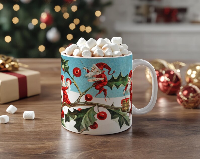 May include: A white ceramic mug with a Christmas scene featuring elves and holly. The mug is filled with marshmallows and a brown liquid, suggesting hot chocolate.