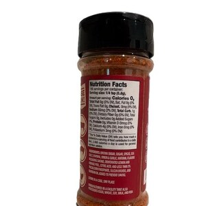 May include: A cylindrical spice container with a black lid and a red label. The label features white text detailing nutrition facts and ingredients. The container is filled with a brown spice blend, visible through the clear portion of the bottle.