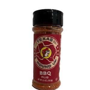 May include: A cylindrical container of Texas Round Up BBQ Rub. The label is red with a circular logo featuring a beaver. The text "BBQ RUB" is below the logo. Net weight is 5.5 oz (155.9g). The lid is black.