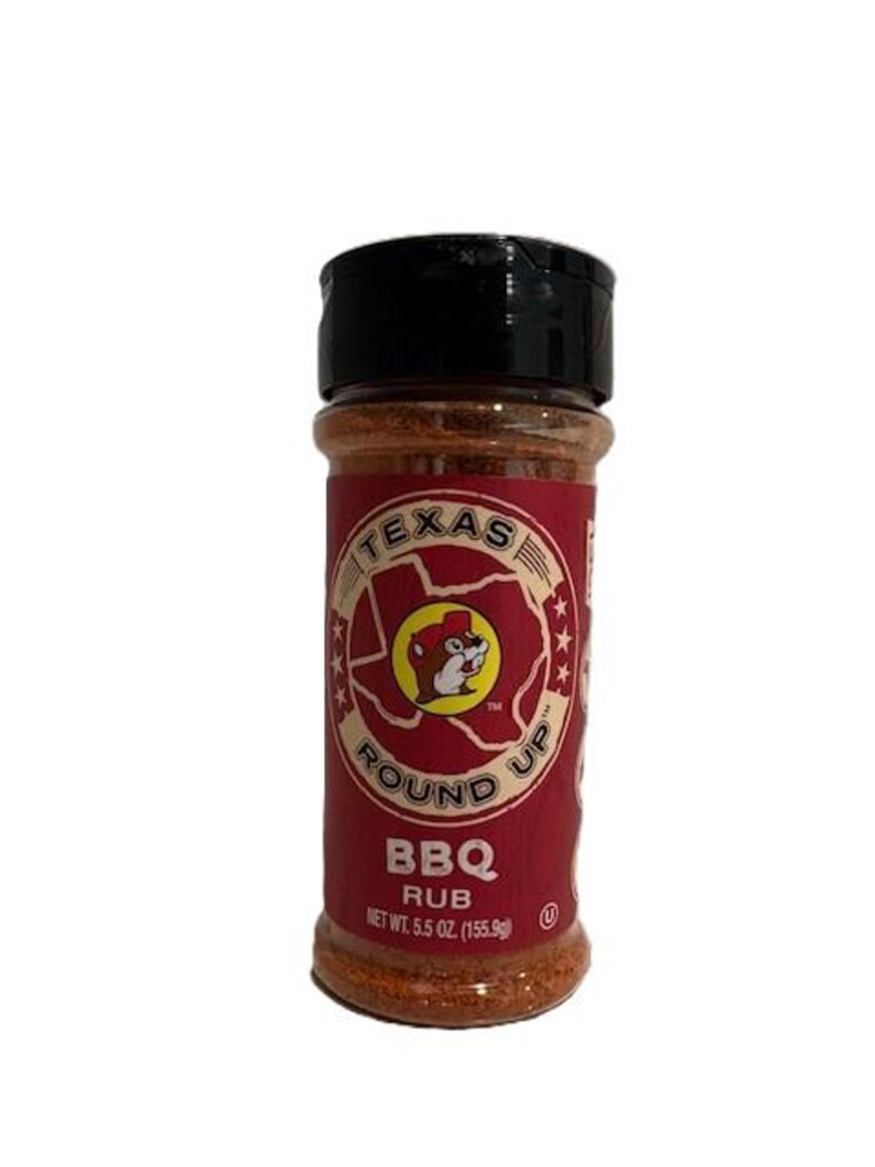 May include: A cylindrical container of Texas Round Up BBQ Rub. The label is red with a circular logo featuring a beaver. The text "BBQ RUB" is below the logo. Net weight is 5.5 oz (155.9g). The lid is black.