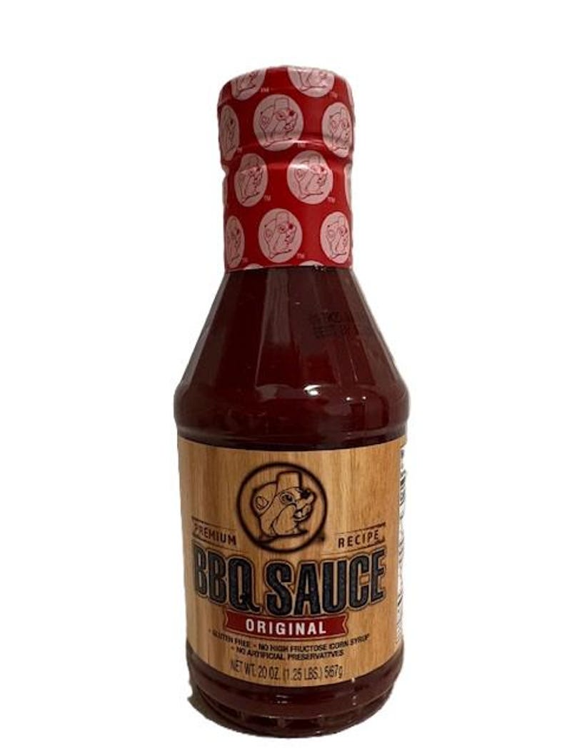May include: A bottle of "Original BBQ Sauce" with a red cap featuring a repeating pattern. The label is brown with the text "BBQ Sauce" and a cartoon beaver. The bottle contains 20 oz (1.25 lbs) of sauce.