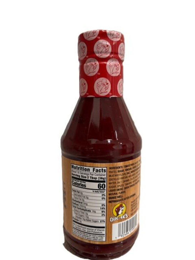 May include: A bottle of Buc-ee's brand sauce with a red cap featuring a repeating logo. The label includes nutrition facts and ingredients. The bottle is filled with a dark red sauce.