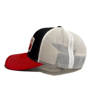 May include: A black, white, and red trucker hat with a mesh back and a curved brim. The front panel is black with a white and red patch. The brim is red.